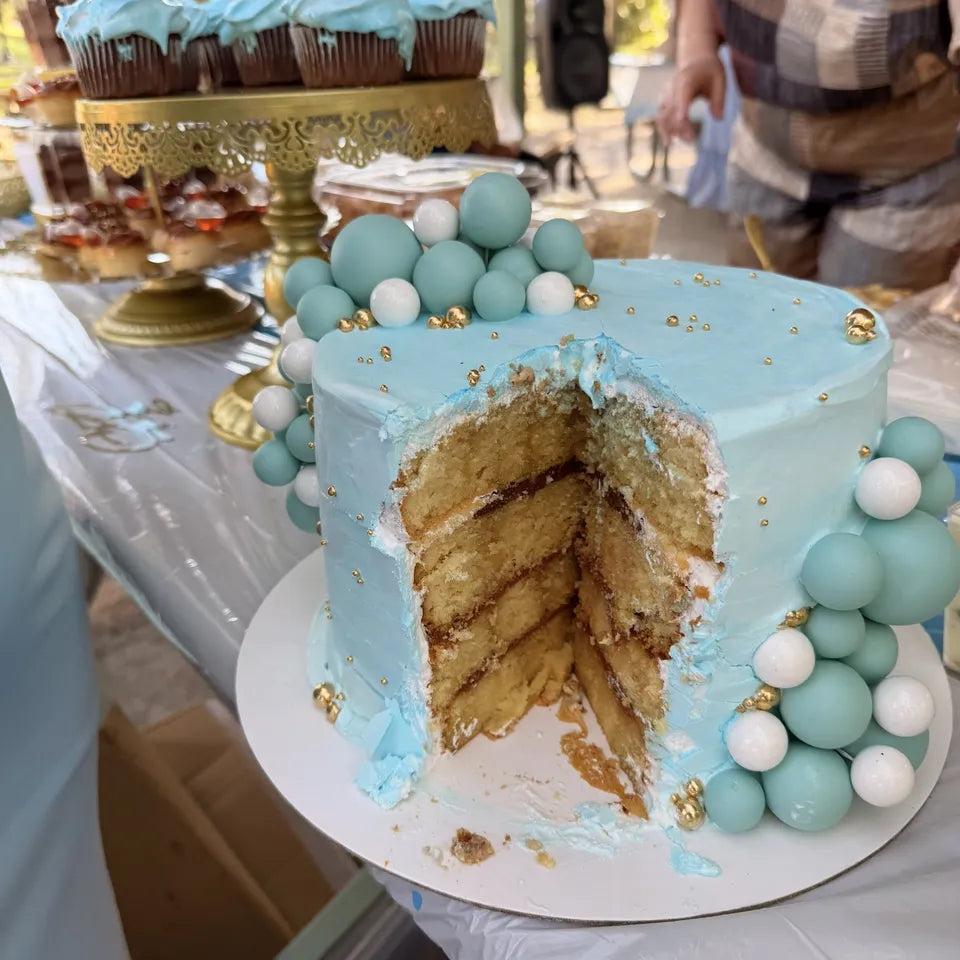 Cake azul cielo con esferas, cortado en la mesa de un baby shower en Miami