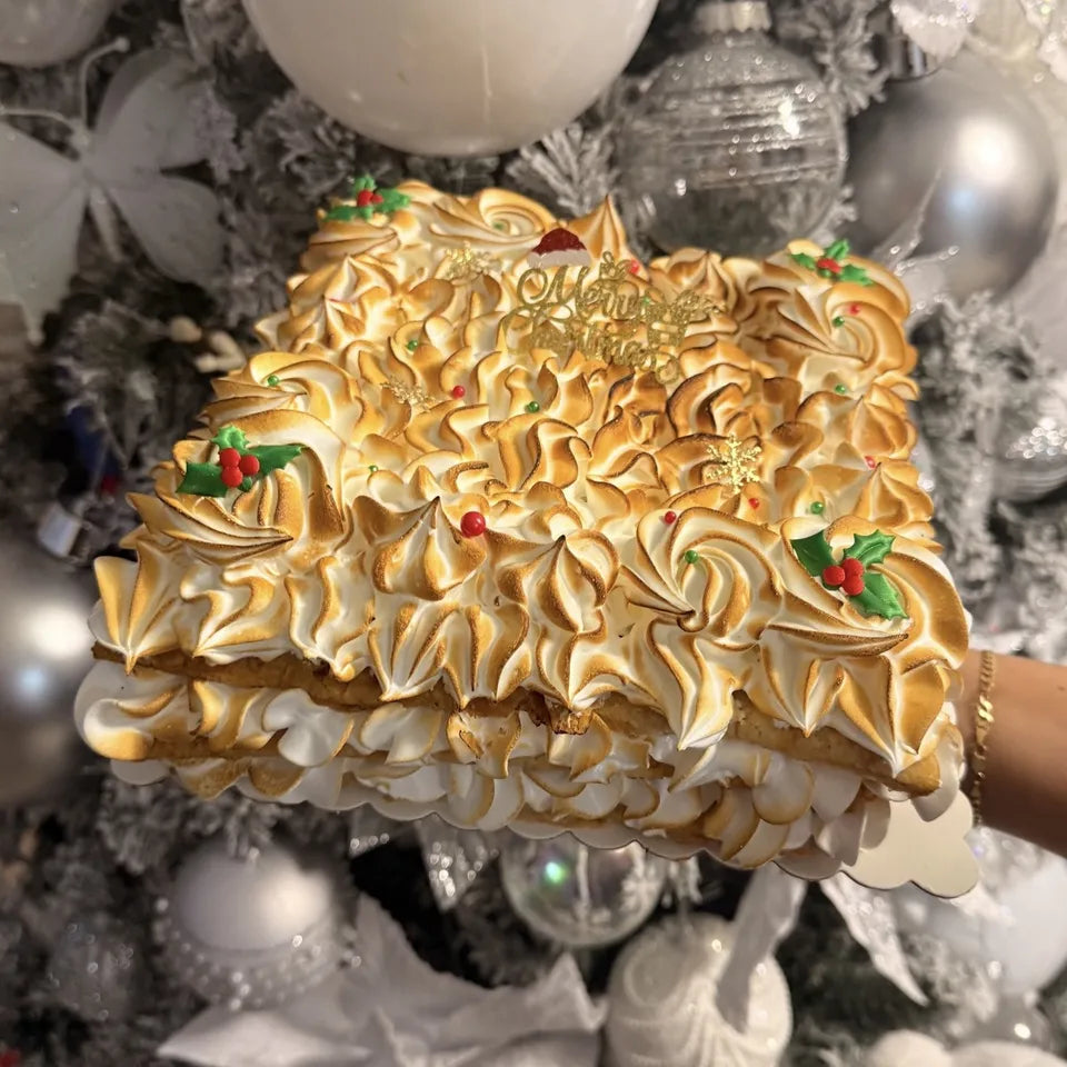 Cake de merengue tostado con adornos navideños delante del árbol de Navidad en Miami
